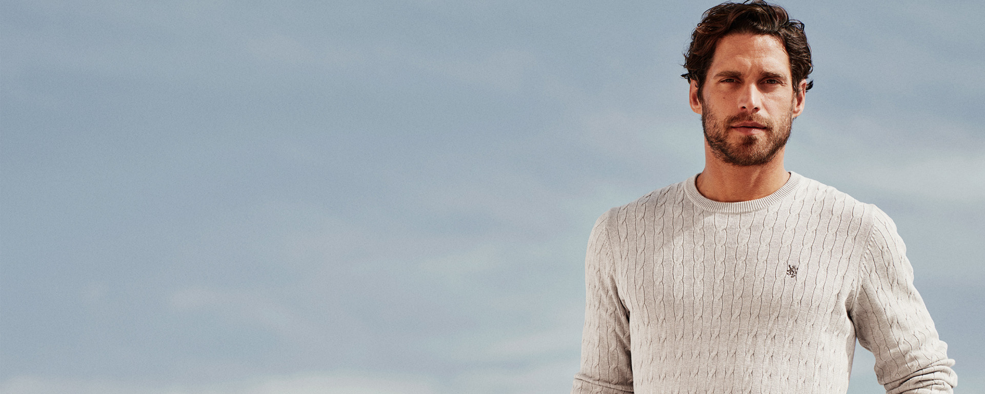 Mann med beige kabelstrikket genser