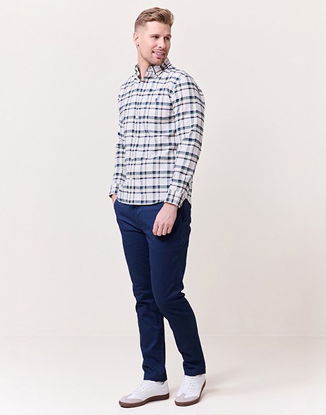 Modell iført rutete skjorte, marineblå chinos og hvite sneakers fra Redford. Et stilrent og avslappet antrekk for herre.